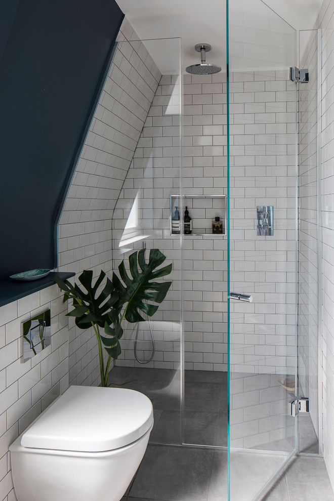 Modern inredning av ett litet en-suite badrum, med en öppen dusch, en vägghängd toalettstol, vit kakel, keramikplattor, cementgolv, grått golv, dusch med gångjärnsdörr och svarta väggar