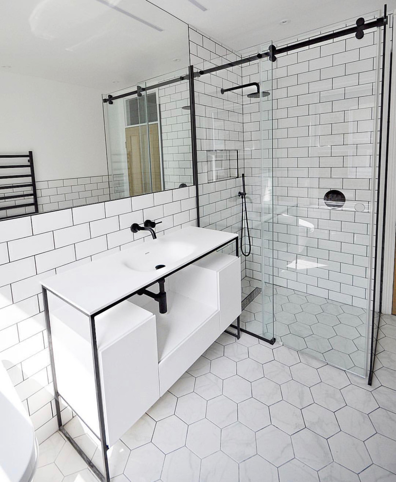Medium sized scandinavian shower room bathroom in London with freestanding cabinets, white cabinets, a walk-in shower, a wall mounted toilet, white tiles, ceramic tiles, white walls, ceramic flooring, solid surface worktops, white floors, a sliding door and white worktops.