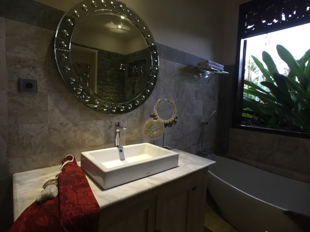 Пример оригинального дизайна: главная ванная комната среднего размера в морском стиле с темными деревянными фасадами, отдельно стоящей ванной, открытым душем, унитазом-моноблоком, серой плиткой, белой плиткой, мраморной плиткой, серыми стенами, полом из галечной плитки, накладной раковиной, мраморной столешницей и открытым душем