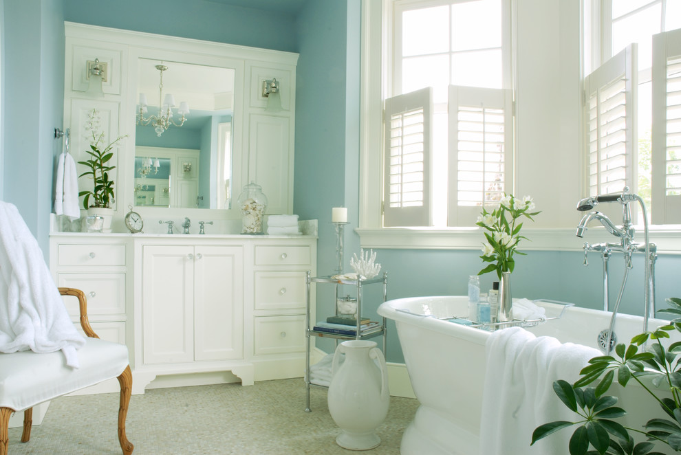 Imagen de cuarto de baño principal marinero con armarios con rebordes decorativos, puertas de armario blancas, bañera exenta, paredes azules, suelo con mosaicos de baldosas y encimera de mármol