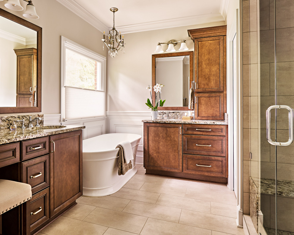 This is an example of a traditional ensuite bathroom in Charlotte with recessed-panel cabinets, brown cabinets, a freestanding bath, beige walls, granite worktops and double sinks.
