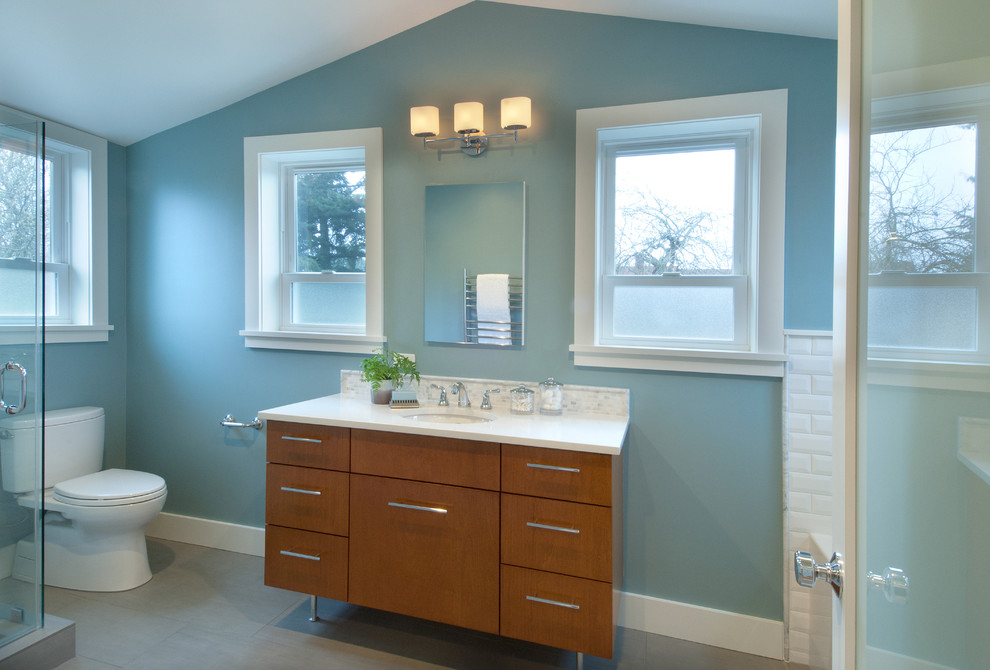 Photo of a large classic ensuite bathroom in Seattle with a submerged sink, medium wood cabinets, quartz worktops, an alcove bath, a corner shower, a one-piece toilet, porcelain tiles, blue walls, porcelain flooring, a hinged door, white worktops and white tiles.