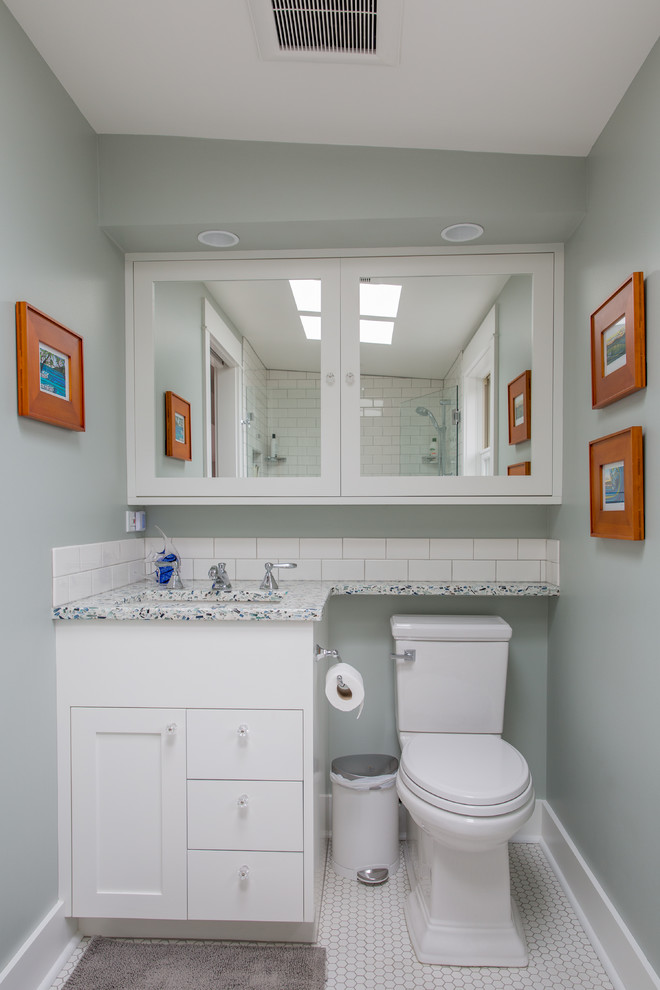 Foto på ett amerikanskt badrum, med släta luckor, vita skåp, en dusch i en alkov, en toalettstol med hel cisternkåpa, vit kakel, tunnelbanekakel, vita väggar, klinkergolv i keramik, ett undermonterad handfat och bänkskiva i återvunnet glas