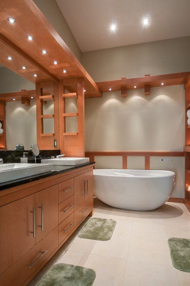 This is an example of a medium sized contemporary ensuite bathroom in DC Metro with a built-in sink, flat-panel cabinets, medium wood cabinets, granite worktops, a freestanding bath, an alcove shower, grey tiles, ceramic tiles, beige walls and ceramic flooring.