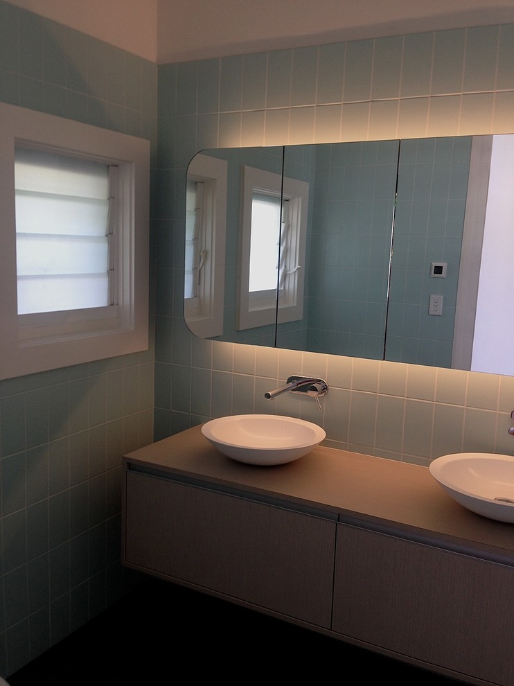 Idée de décoration pour une salle de bain principale minimaliste en bois clair de taille moyenne avec un placard à porte plane, une baignoire indépendante, un combiné douche/baignoire, WC à poser, un carrelage bleu, des carreaux de céramique, un mur bleu, un sol en carrelage de porcelaine, une vasque et un plan de toilette en stratifié.