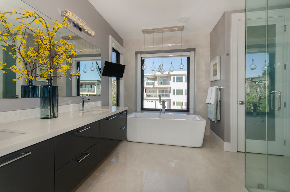 Large modern ensuite bathroom in Vancouver with flat-panel cabinets, black cabinets, a freestanding bath, a corner shower, grey walls, a submerged sink, white tiles, glass tiles, porcelain flooring and solid surface worktops.
