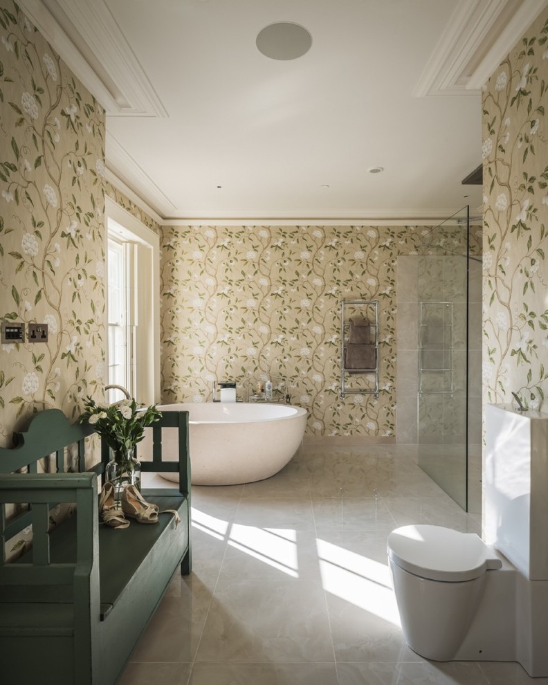 Klassisk inredning av ett en-suite badrum, med ett fristående badkar, en toalettstol med separat cisternkåpa, beige väggar och grått golv
