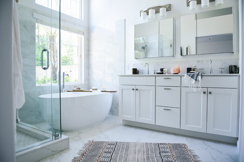 Photo of a large classic ensuite bathroom in San Diego with shaker cabinets, white cabinets, a freestanding bath, a walk-in shower, a two-piece toilet, white tiles, porcelain tiles, white walls, porcelain flooring, a submerged sink, engineered stone worktops, white floors, a hinged door and white worktops.