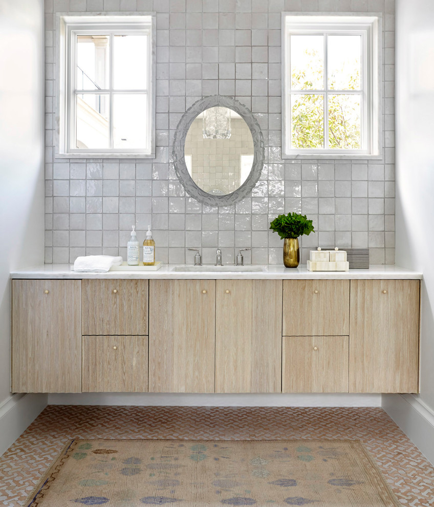 Immagine di una stanza da bagno tradizionale con ante lisce, ante in legno chiaro, piastrelle grigie, pareti bianche, pavimento con piastrelle a mosaico, lavabo sottopiano, pavimento multicolore e top bianco