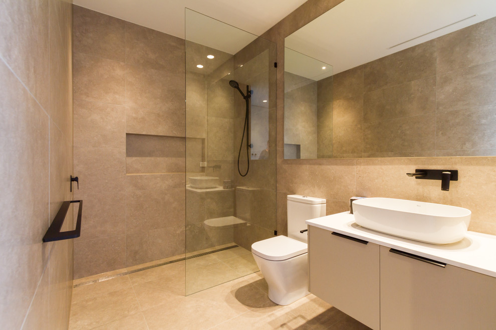 This is an example of an expansive modern ensuite bathroom in Melbourne with flat-panel cabinets, black cabinets, a freestanding bath, grey tiles, stone slabs, white walls, porcelain flooring, a built-in sink, engineered stone worktops, grey floors and white worktops.