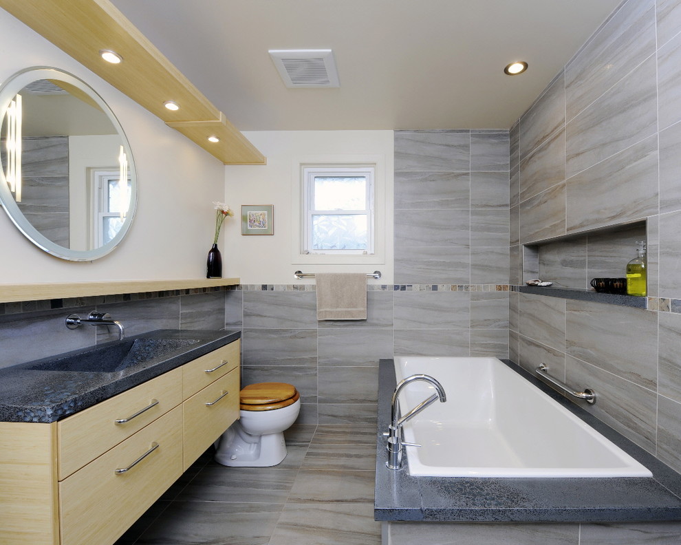 Foto de cuarto de baño contemporáneo con lavabo integrado, armarios con paneles lisos, puertas de armario de madera clara, bañera encastrada y baldosas y/o azulejos marrones
