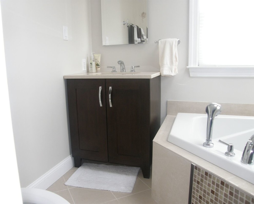 Cette photo montre une salle de bain tendance en bois foncé de taille moyenne avec un placard à porte shaker, une baignoire posée, un mur gris, un sol en carrelage de céramique, un lavabo encastré et un sol beige.