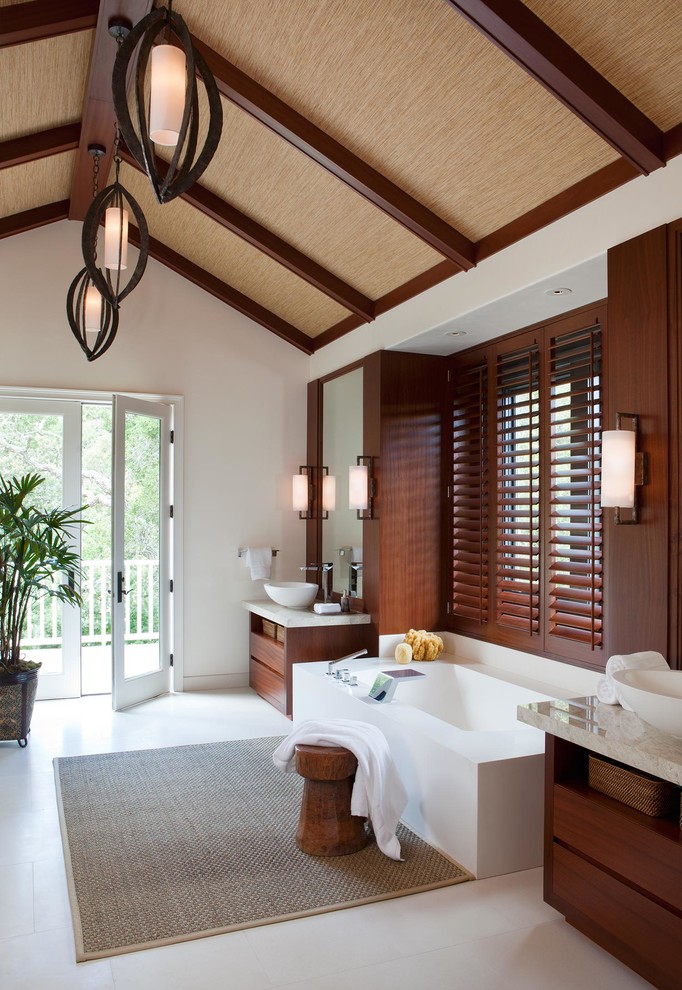 Ispirazione per una stanza da bagno padronale tropicale con ante lisce, ante in legno bruno, vasca freestanding e lavabo a bacinella