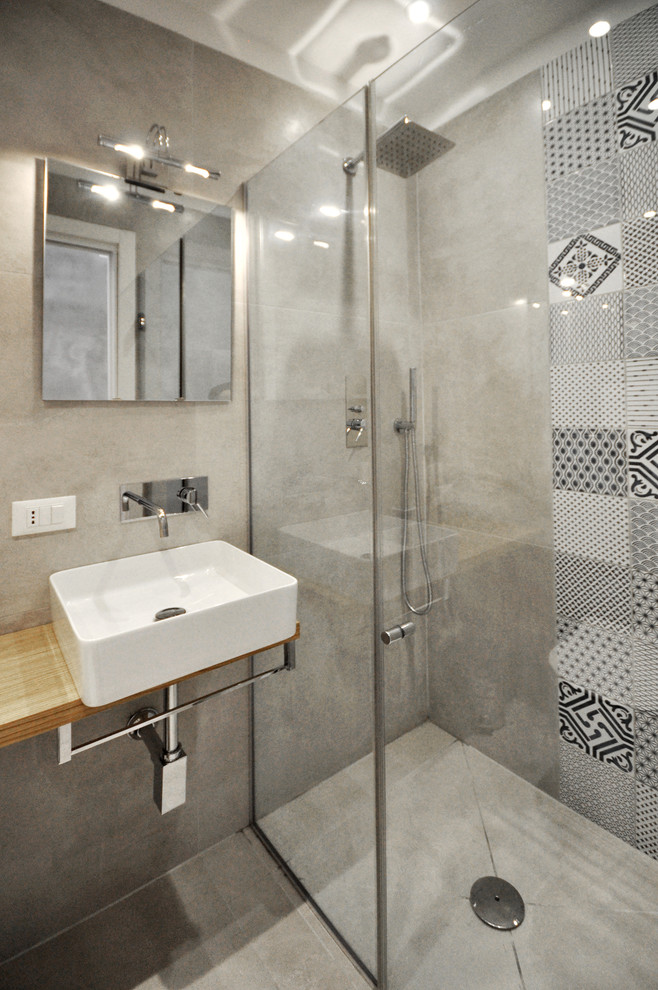 Exemple d'une salle d'eau moderne en bois brun avec un placard sans porte, une douche ouverte, un carrelage gris, des carreaux de porcelaine, une vasque et un plan de toilette en bois.