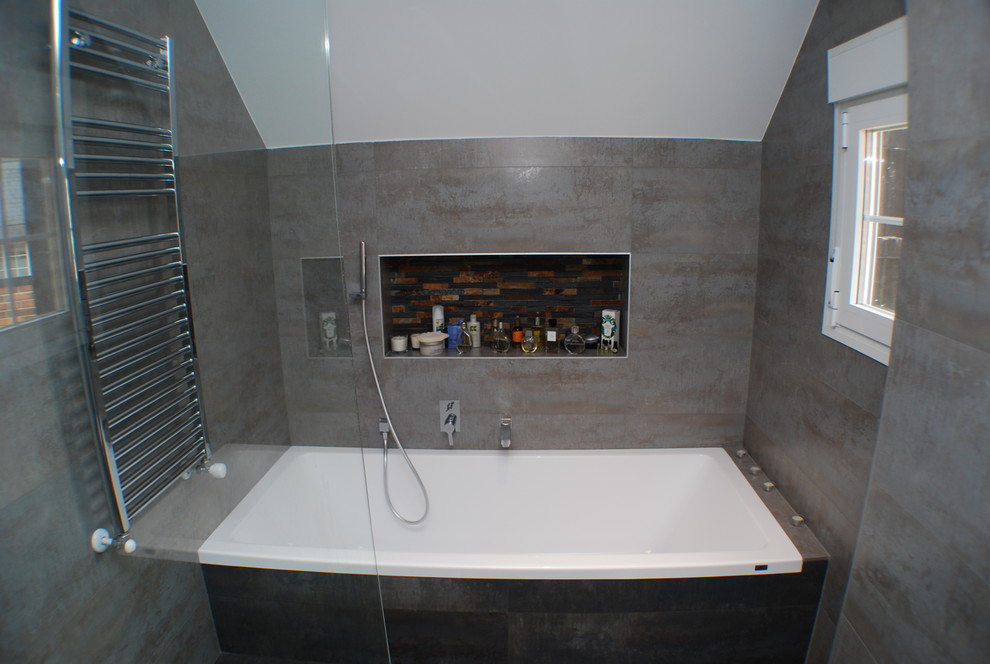 Ejemplo de cuarto de baño principal minimalista de tamaño medio con combinación de ducha y bañera, baldosas y/o azulejos grises, baldosas y/o azulejos de cerámica, paredes grises, suelo de baldosas de cerámica y bañera encastrada