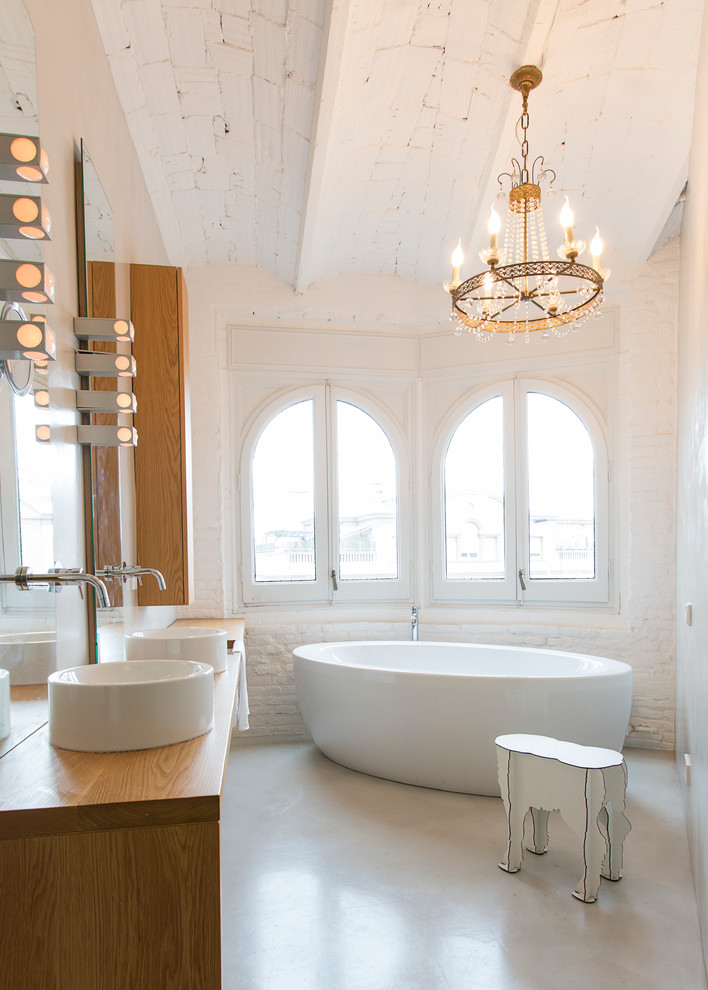 Стильный дизайн: главная ванная комната среднего размера в современном стиле с отдельно стоящей ванной, белыми стенами, бетонным полом, настольной раковиной, столешницей из дерева, открытыми фасадами, серой плиткой и серым полом - последний тренд
