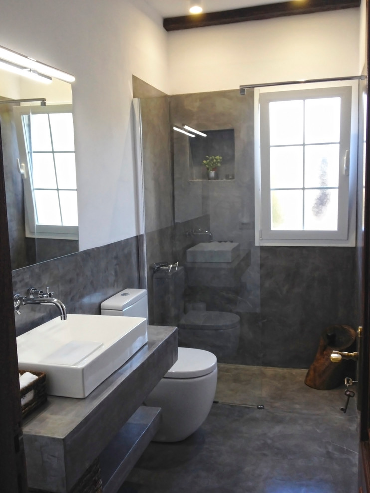 Imagen de cuarto de baño bohemio de tamaño medio con ducha a ras de suelo, sanitario de dos piezas, paredes blancas, aseo y ducha, lavabo sobreencimera y microcemento