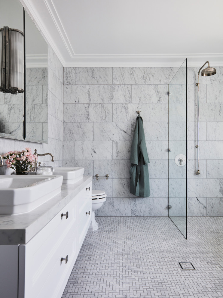 Klassisk inredning av ett grå grått en-suite badrum, med luckor med infälld panel, vita skåp, en kantlös dusch, marmorkakel, grå väggar, ett fristående handfat, marmorbänkskiva och med dusch som är öppen