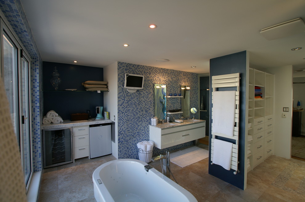 Example of a large zen master blue tile limestone floor freestanding bathtub design in Philadelphia with glass-front cabinets, white cabinets, a one-piece toilet, blue walls, an undermount sink and marble countertops