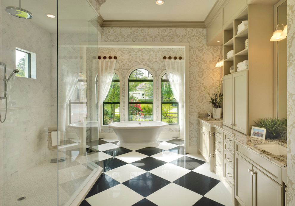 Idée de décoration pour une salle de bain principale tradition avec un placard avec porte à panneau encastré, des portes de placard beiges, une baignoire indépendante, un carrelage blanc, un mur multicolore, un lavabo encastré et du carrelage bicolore.