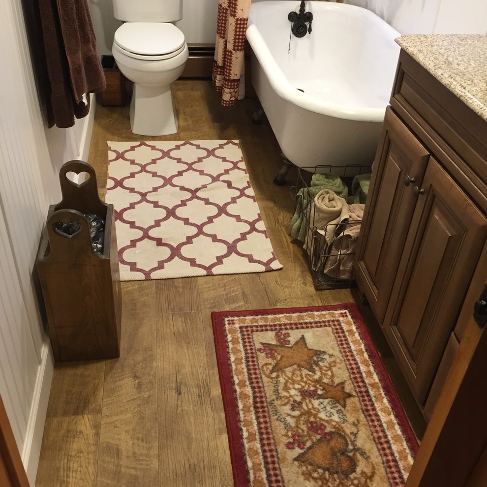 Exemple d'une petite salle de bain nature en bois brun avec un placard avec porte à panneau surélevé, une baignoire sur pieds, WC séparés, un mur jaune, un sol en vinyl, un lavabo encastré et un plan de toilette en granite.