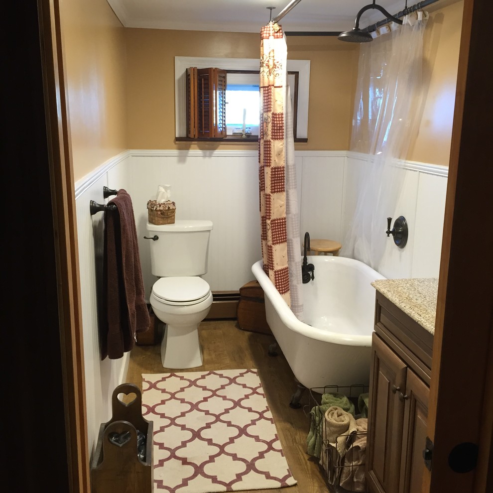 Design ideas for a small farmhouse bathroom in Philadelphia with raised-panel cabinets, medium wood cabinets, a claw-foot bath, a two-piece toilet, yellow walls, vinyl flooring, a submerged sink and granite worktops.