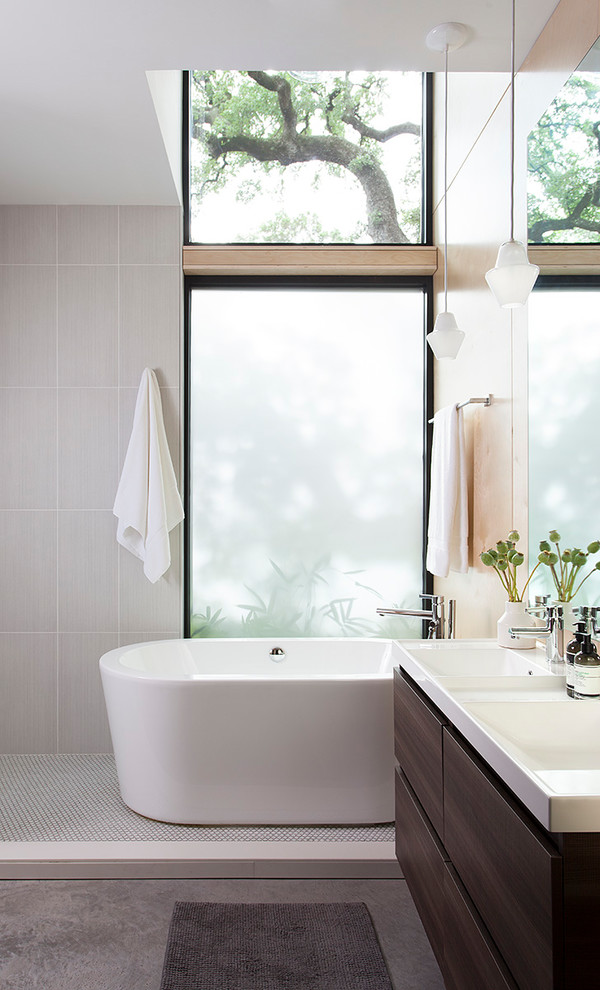 На фото: главная ванная комната в стиле ретро с плоскими фасадами, темными деревянными фасадами, отдельно стоящей ванной, серой плиткой, серыми стенами, монолитной раковиной, серым полом и белой столешницей