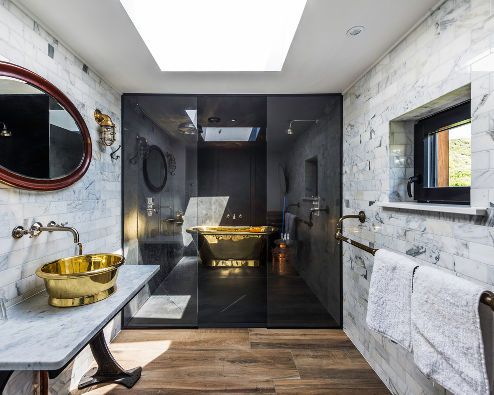На фото: большая ванная комната в стиле фьюжн с отдельно стоящей ванной, серыми стенами, настольной раковиной, мраморной столешницей, коричневым полом и открытым душем