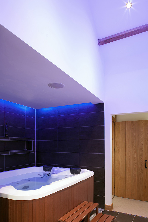 Idée de décoration pour une salle de bain principale minimaliste de taille moyenne avec un bain bouillonnant, un carrelage noir, des carreaux de céramique, un mur blanc et un sol en carrelage de céramique.