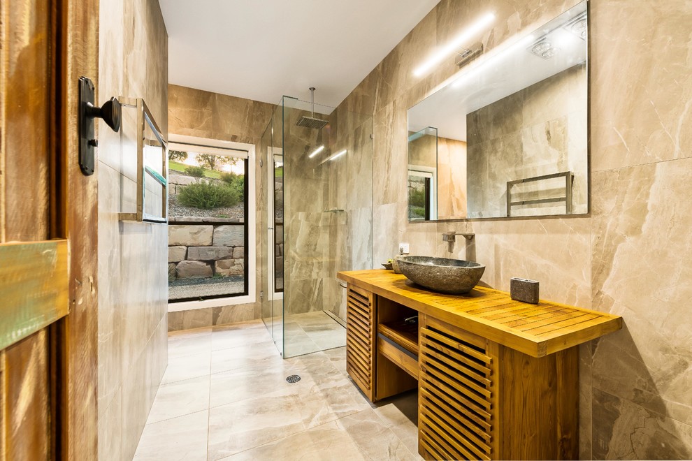Inspiration for a medium sized rural bathroom in Other with louvered cabinets, brown cabinets, an alcove shower, marble tiles, a vessel sink, wooden worktops, beige walls, marble flooring, beige floors, a hinged door and beige worktops.