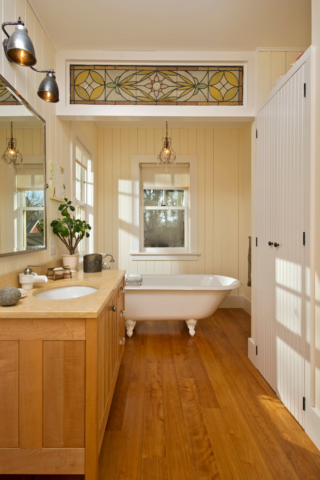 Bild på ett mellanstort lantligt badrum, med ett undermonterad handfat, ett badkar med tassar, skåp i mellenmörkt trä och beige väggar