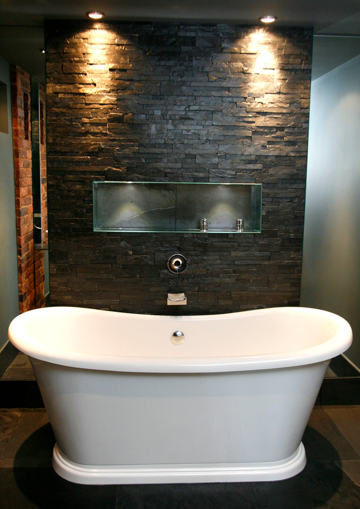 Modelo de cuarto de baño principal contemporáneo de tamaño medio con bañera exenta, ducha abierta, sanitario de dos piezas, baldosas y/o azulejos grises, baldosas y/o azulejos de piedra, paredes grises y suelo de pizarra