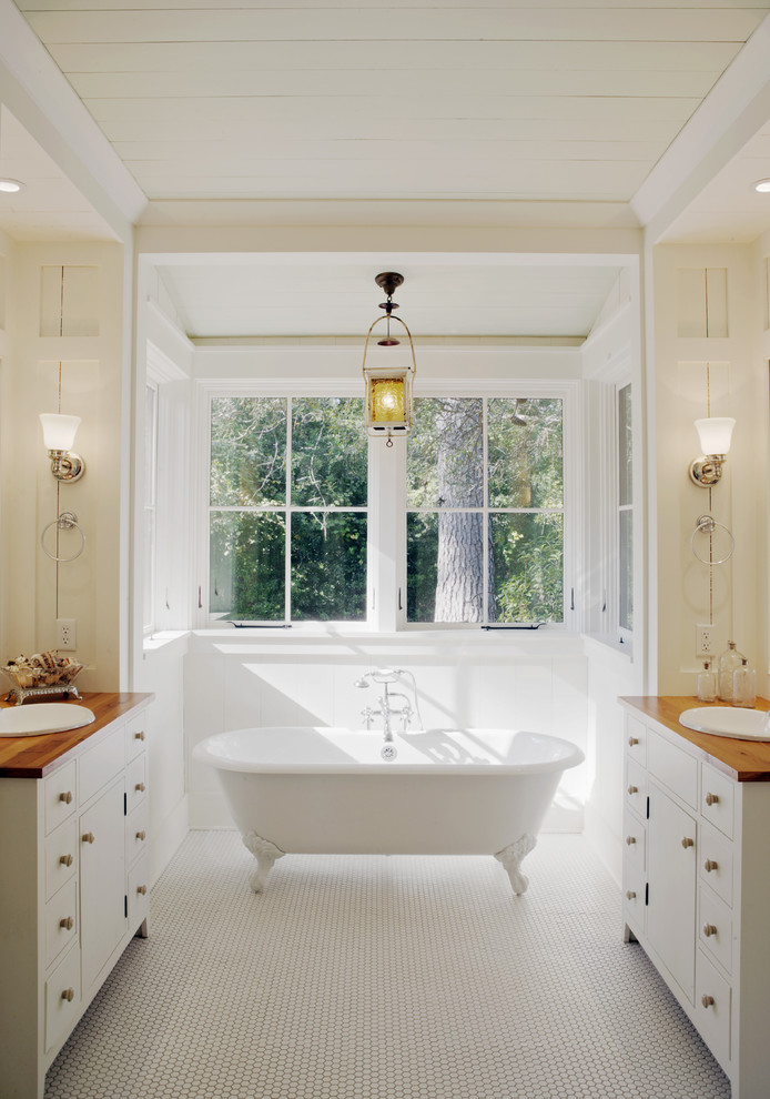 Cette photo montre une salle de bain montagne avec une baignoire sur pieds, un plan de toilette en bois, un plan de toilette marron et une fenêtre.