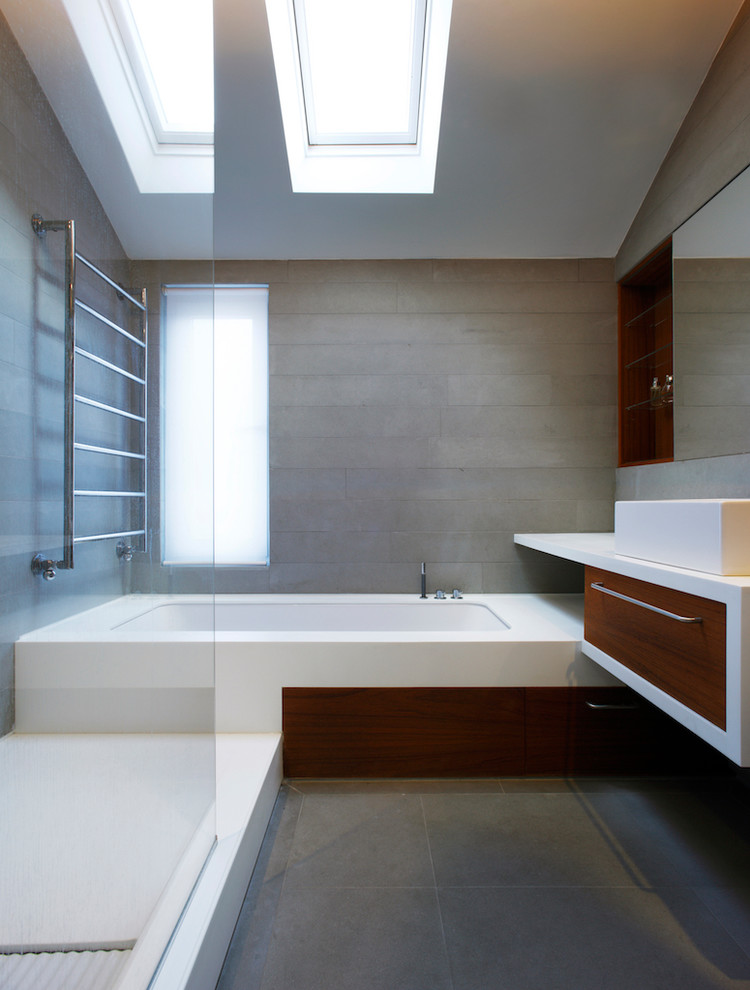 Inspiration for a medium sized contemporary family bathroom in London with open cabinets, brown cabinets, a built-in bath, a walk-in shower, a wall mounted toilet, grey tiles, stone tiles, grey walls, slate flooring, a built-in sink, solid surface worktops, grey floors and an open shower.