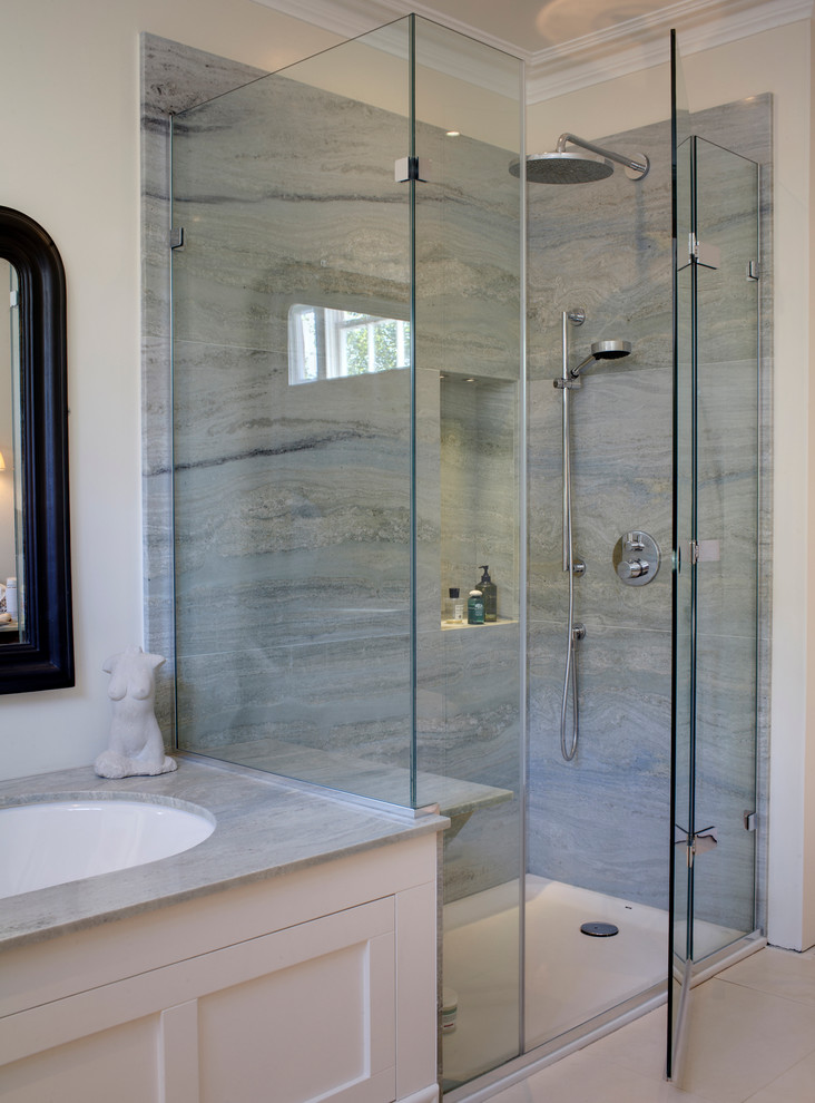 Eklektisk inredning av ett mellanstort badrum, med ett undermonterad handfat, skåp i shakerstil, beige skåp, marmorbänkskiva, en hörndusch, grå kakel, stenhäll, beige väggar och kalkstensgolv