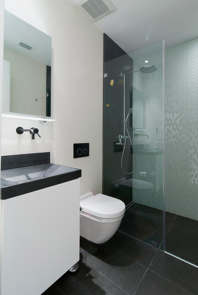 Kleines Modernes Badezimmer mit Einbauwaschbecken, Wandtoilette, flächenbündigen Schrankfronten, weißen Schränken, schwarzen Fliesen, Steinfliesen, weißer Wandfarbe und Porzellan-Bodenfliesen in Miami
