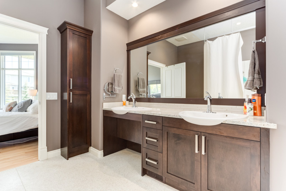 Photo of a large traditional ensuite bathroom in Calgary with a vessel sink, shaker cabinets, dark wood cabinets, engineered stone worktops, a built-in shower, a two-piece toilet, white tiles, porcelain tiles, beige walls and lino flooring.