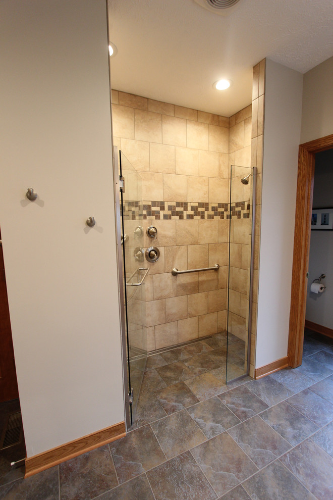 This is an example of a large classic ensuite bathroom in Cleveland with flat-panel cabinets, light wood cabinets, a freestanding bath, a corner shower, a two-piece toilet, beige tiles, porcelain tiles, beige walls, porcelain flooring, an integrated sink, solid surface worktops, brown floors and a hinged door.
