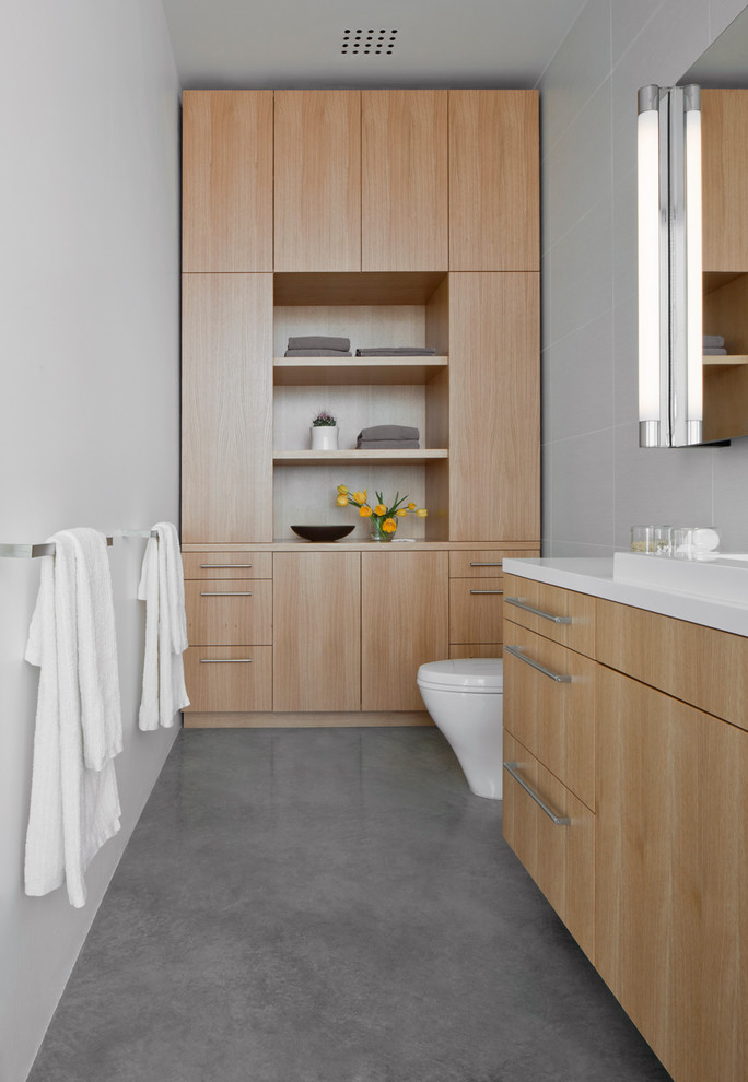 Exempel på ett litet modernt badrum, med släta luckor, skåp i ljust trä, porslinskakel, vita väggar, betonggolv, bänkskiva i akrylsten, ett nedsänkt handfat och grå kakel