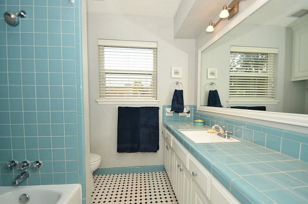 Exempel på ett mellanstort klassiskt badrum för barn, med ett undermonterad handfat, luckor med infälld panel, vita skåp, kaklad bänkskiva, ett badkar i en alkov, en dusch/badkar-kombination, en toalettstol med separat cisternkåpa, blå kakel, keramikplattor, vita väggar och mosaikgolv