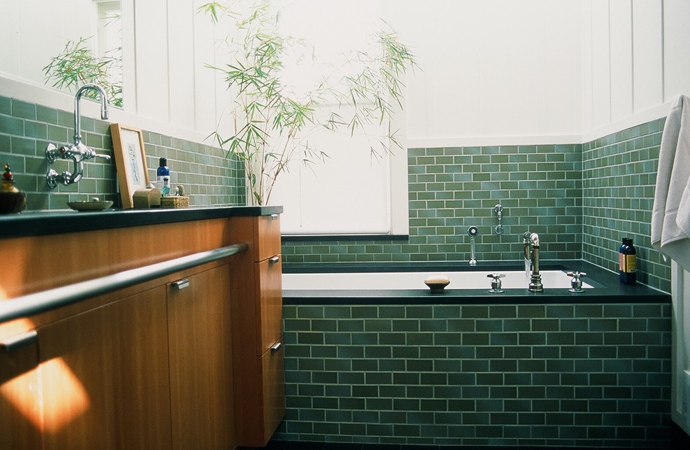 Cette image montre une salle de bain design avec une baignoire en alcôve, un carrelage vert et un carrelage métro.