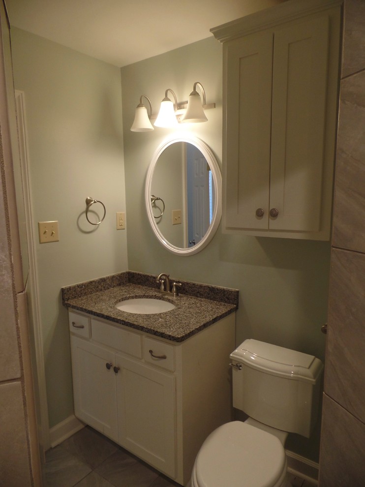 Cette photo montre une petite salle d'eau chic avec un lavabo encastré, un placard à porte shaker, des portes de placard blanches, un plan de toilette en granite, une douche d'angle, WC séparés, des carreaux de porcelaine, un mur vert et un sol en carrelage de porcelaine.