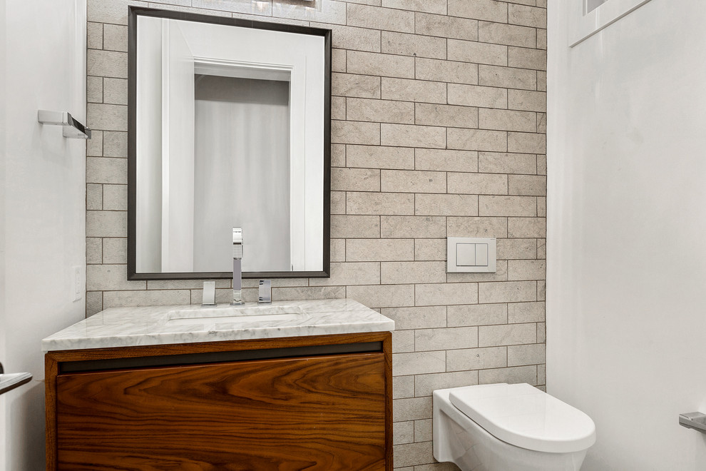 Esempio di una stanza da bagno minimal di medie dimensioni con consolle stile comò, ante in legno scuro, WC sospeso, piastrelle grigie, piastrelle in pietra, pareti bianche, lavabo sottopiano e top in marmo