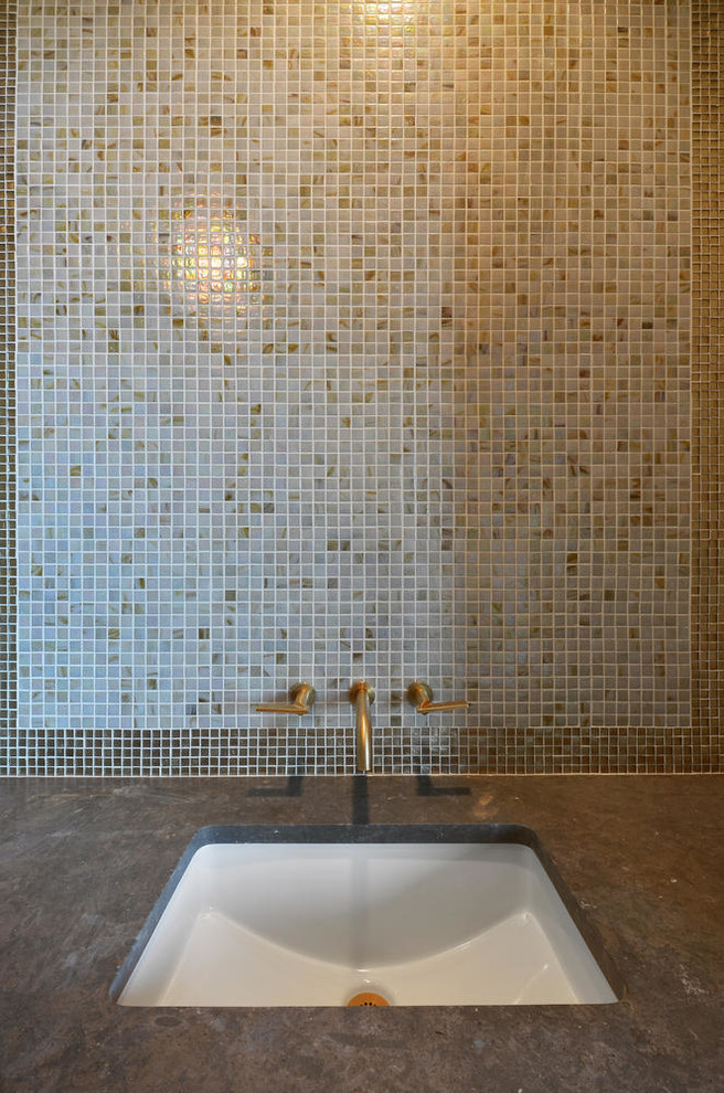 Foto di una stanza da bagno chic con top in pietra calcarea, piastrelle di vetro e lavabo sottopiano