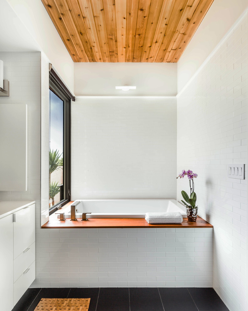 Inspiration för ett funkis badrum, med släta luckor, vita skåp, ett platsbyggt badkar, vit kakel och tunnelbanekakel