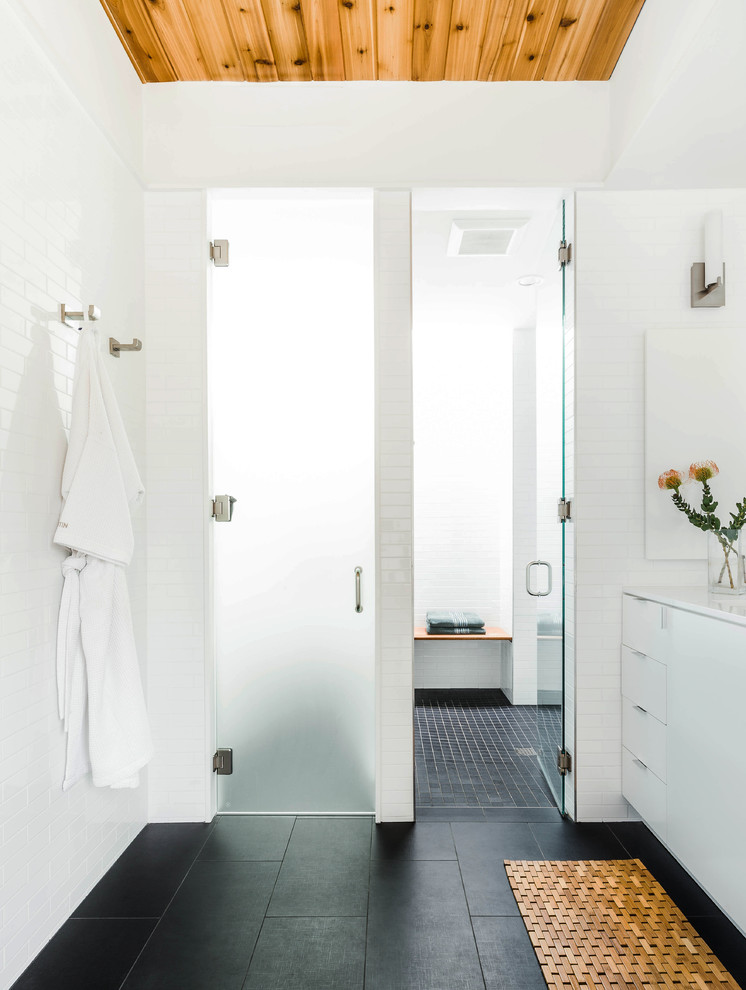 オースティンにあるコンテンポラリースタイルのおしゃれな浴室 (フラットパネル扉のキャビネット、白いキャビネット、アルコーブ型シャワー、白いタイル、サブウェイタイル、黒い床) の写真