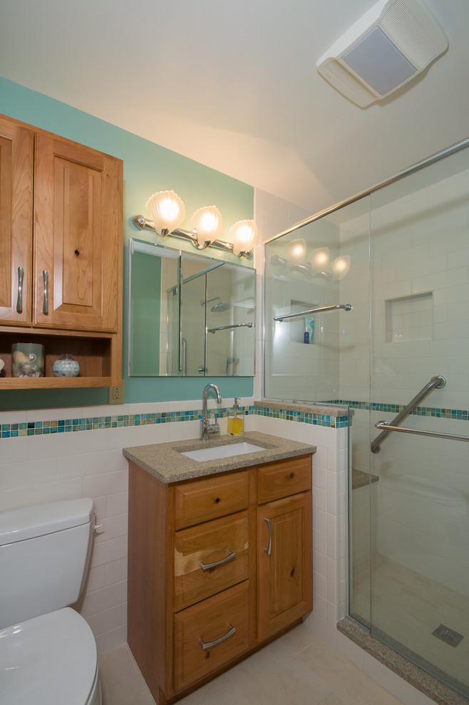 Example of an eclectic blue tile ceramic tile corner shower design in Columbus with an undermount sink, raised-panel cabinets, medium tone wood cabinets, granite countertops, a two-piece toilet and blue walls