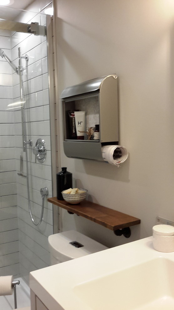Aménagement d'une petite salle d'eau industrielle avec un placard à porte shaker, des portes de placard grises, WC à poser, un carrelage gris, des carreaux de céramique, un mur gris, un sol en brique et un plan de toilette en surface solide.
