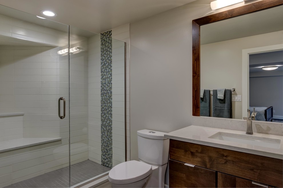 Réalisation d'une salle de bain design en bois foncé de taille moyenne avec un placard à porte plane, WC à poser, un mur beige, un lavabo encastré, un plan de toilette en quartz modifié, une cabine de douche à porte battante et un plan de toilette beige.
