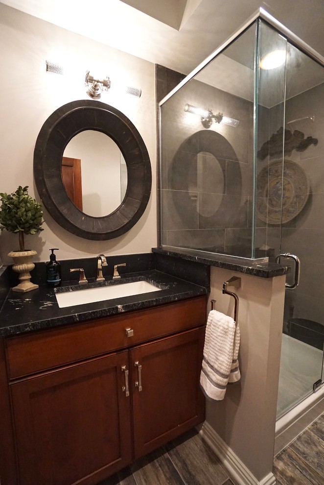 Immagine di una piccola stanza da bagno padronale contemporanea con consolle stile comò, ante in legno bruno, doccia ad angolo, piastrelle grigie, lavabo sottopiano, pavimento multicolore e top nero